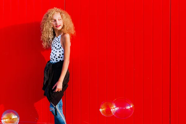 Dívka v pubertě na pozadí červené zdi — Stock fotografie