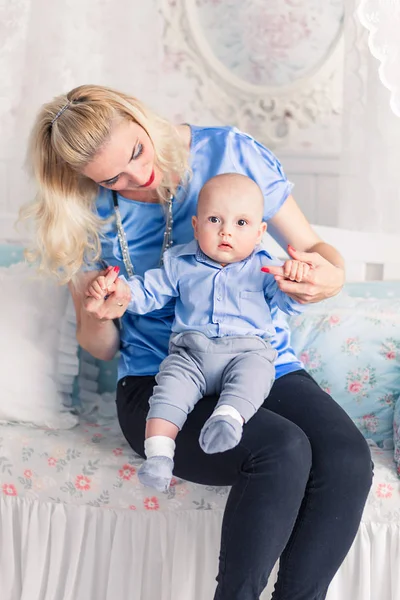 Maman joue avec le bébé dans la crèche et sourit — Photo