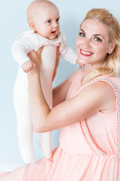 Мама в розовом платье держит своего маленького сына на руках и улыбается — стоковое фото