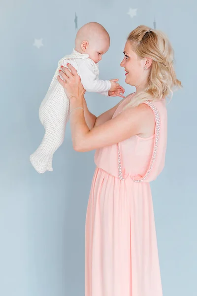 Mère joue et vomit un enfant dans la chambre des enfants sur le fond du mur bleu — Photo