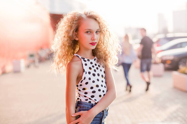 teen girl on a city street posing in the rays of the evening sun