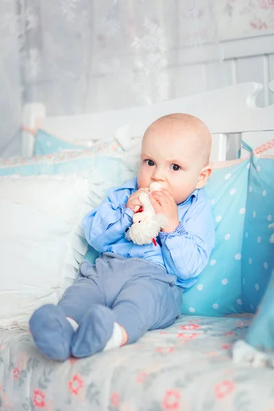 Chlapeček v modrých šatech, který sedí na pohovce — Stock fotografie