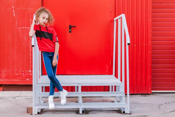 Jeune fille à la mode posant contre un mur rouge — Photo