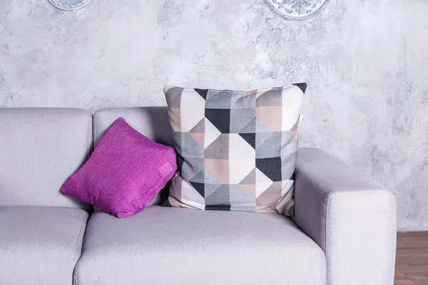 Canapé gris avec oreillers violets dans une chambre avec un mur gris — Photo