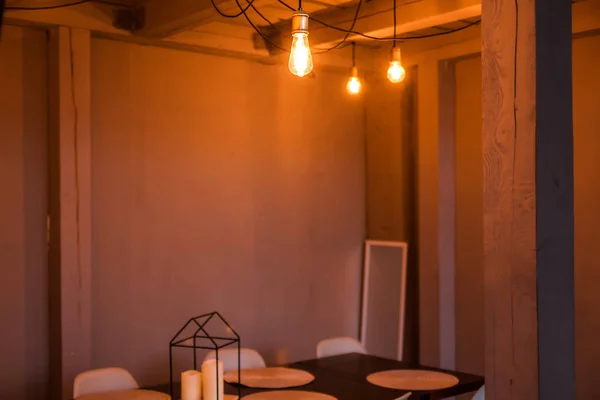 Вечерний свет от лампочки освещает деревянный обеденный стол и стулья — стоковое фото