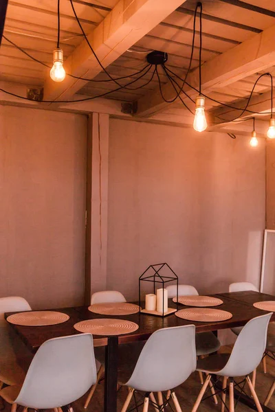 Вечерний свет от лампочки освещает деревянный обеденный стол и стулья — стоковое фото