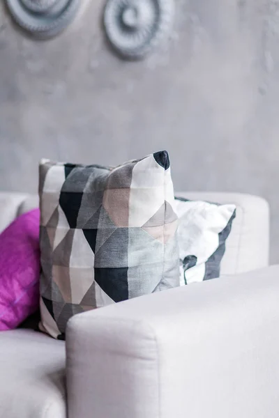 Sofá gris con una variedad de almohadas en una habitación con una pared gris — Foto de Stock