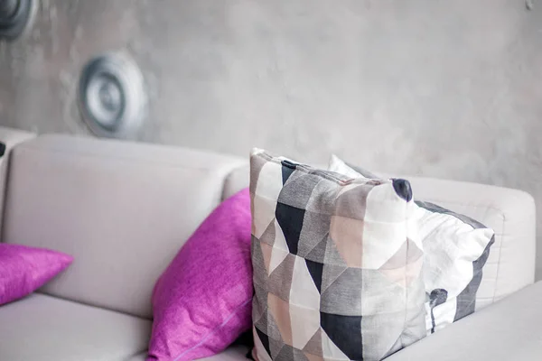 Сірий диван з фіолетовими подушками в кімнаті з сірою стіною — стокове фото