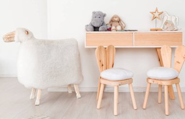 Çocuk odasında tavşan kulakları ile 2 sandalye, oyuncaklar ve büyük bir koyun ile bir masa
