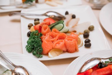 ziyafette yeşilliklerle süslenmiş kırmızı balık, zeytin ve zeytinli bir tabak var.