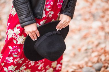 Kırmızı bir elbise nin arka planında kadın ellerde siyah şapka