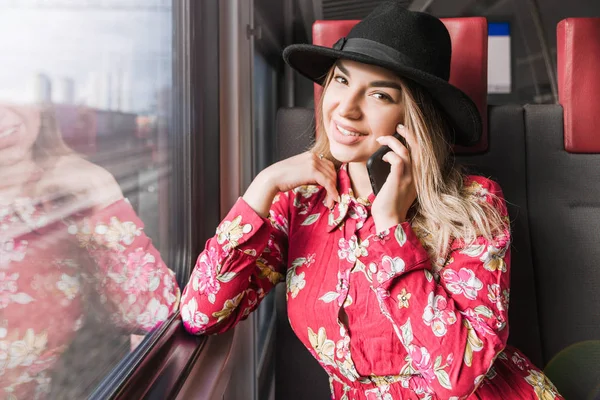 Beautiful girl sitting alone in a train and talking on a mobile phone — Stock Photo, Image