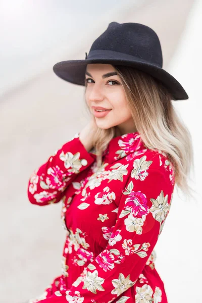 Schönes Mädchen in rotem Kleid und schwarzem Hut posiert für die Kamera — Stockfoto