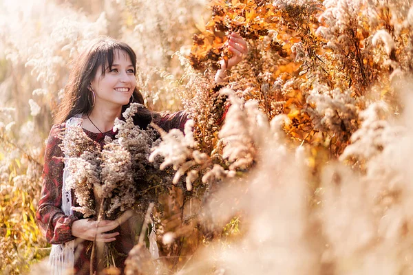 Feliz joven posando entre flores secas de otoño —  Fotos de Stock