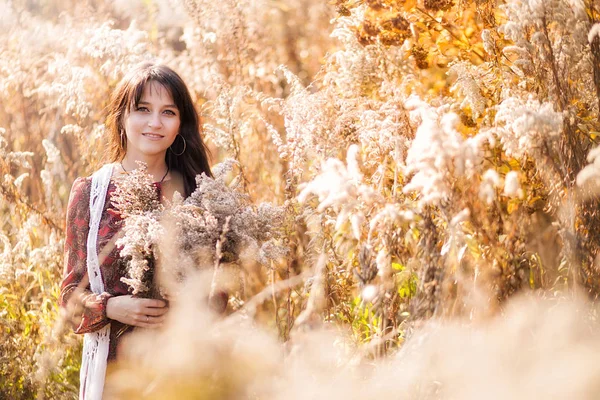 가을 말린 꽃들 사이에서 포즈를 취하는 행복한 젊은 여성 — 스톡 사진