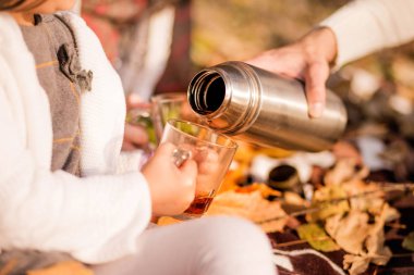 Çocuk elleriyle kupa. Bir termos sıcak çay bir bardak içine dökülür