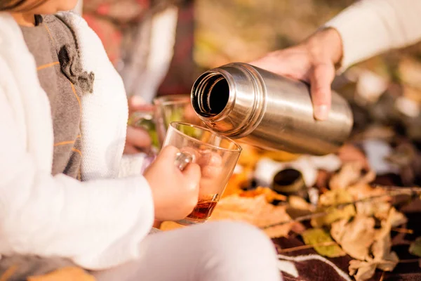 Çocuk elleriyle kupa. Bir termos sıcak çay bir bardak içine dökülür