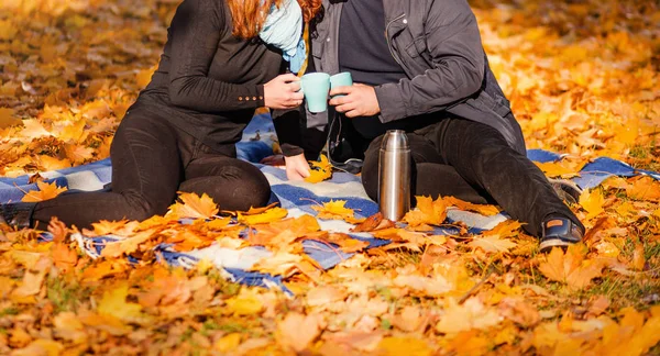 Любящая пара - мужчина и женщина - проводят время вместе в осеннем парке, пьют чай из термоса — стоковое фото
