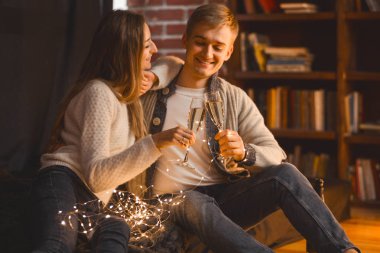 erkek ve kadın akşam ayarında rahat bir odada şampanya içmek