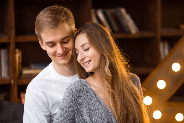 Pareja enamorada en una acogedora habitación con una gran lámpara en forma de carta — Foto de Stock