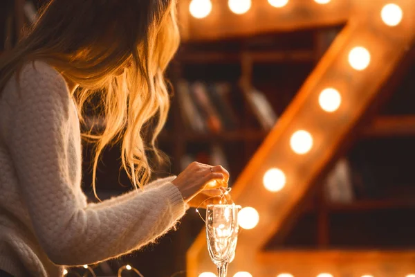 Chica decora una copa de champán con luces de Navidad —  Fotos de Stock