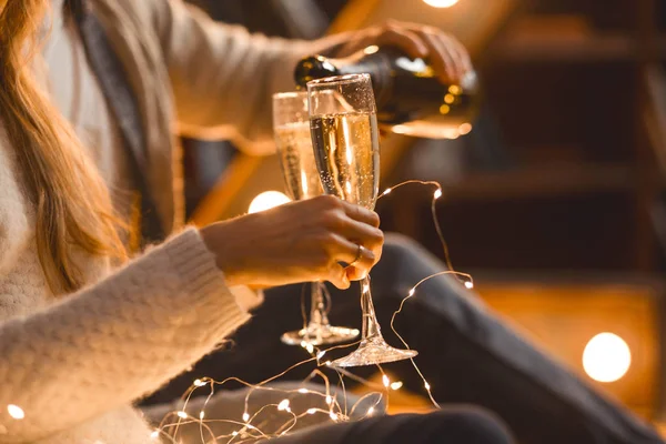 man and woman drink champagne in a cozy room in the evening setting