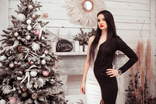 Girl in a black dress posing near a New Year tree — Stock Photo, Image