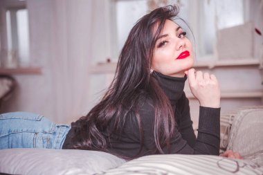 Güzel ve şehvetli esmer kız yatakta poz veriyor.