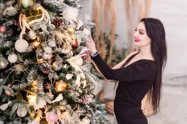 Девушка в черном платье позирует возле новогодней елки — стоковое фото