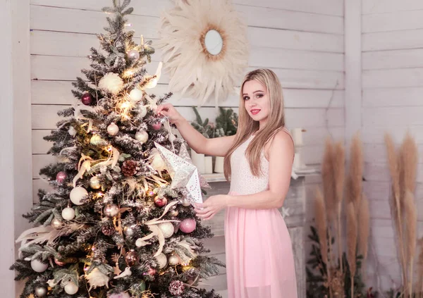 Dívka v růžových šatech zdobí vánoční stromek — Stock fotografie