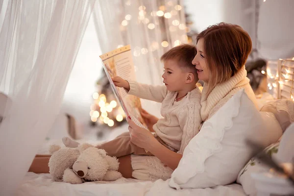 Mamá lee un libro a su hijo en una acogedora noche de invierno — Foto de Stock