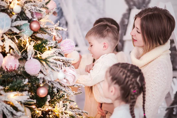 Mãe com seus filhos decora uma árvore de Natal — Fotografia de Stock