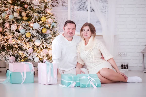 Małżeństwo siedzi wśród prezentów w pobliżu Nowego Roku drzewa — Zdjęcie stockowe