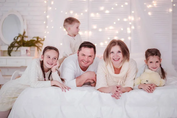 Rodzina w noworocznym wnętrzu. Rodzina leży na łóżku i patrzy w kamerę. — Zdjęcie stockowe