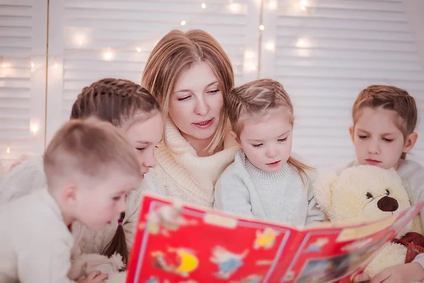 Madre con muchos niños lee cuentos de Navidad a los niños — Foto de Stock