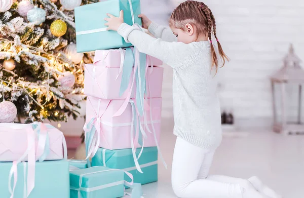 Ευτυχισμένο κοριτσάκι χτίζει μια πυραμίδα από δώρα κοντά στο δέντρο της Πρωτοχρονιάς — Φωτογραφία Αρχείου