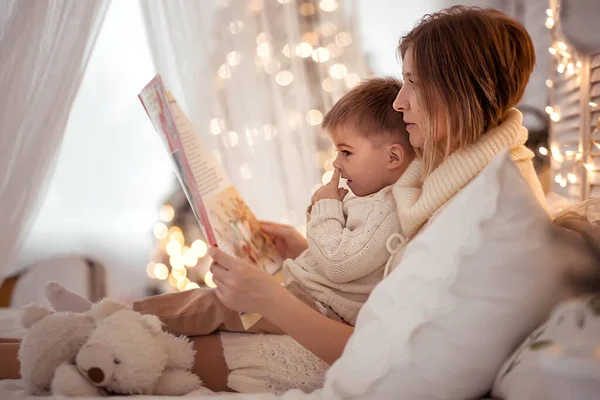 Mamá lee un libro a su hijo en una acogedora noche de invierno — Foto de Stock