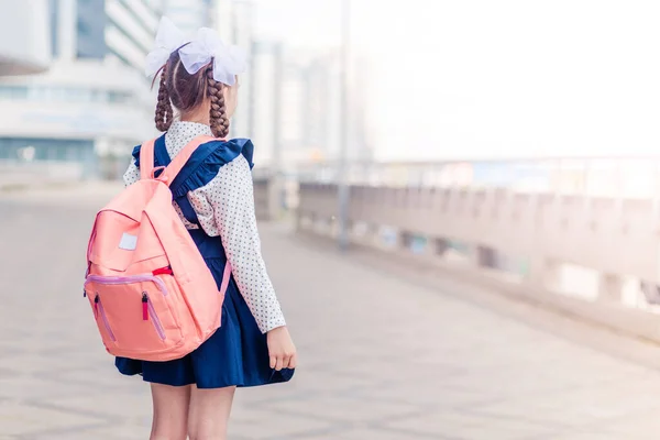 Dziewczyna Niebieskiej Sukience Szkolnej Różowym Plecakiem Plecach Warkoczami Pokłony Stoi — Zdjęcie stockowe