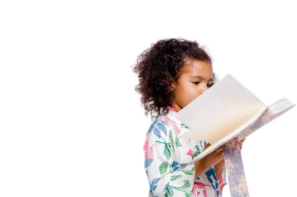 Pequeña chica afroamericana bastante de moda en vestido floral blanco mirando el cuaderno — Foto de Stock