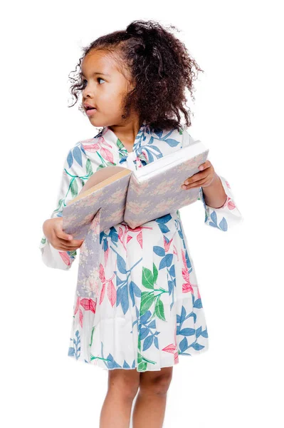 Pequeña linda chica afroamericana de moda en vestido floral blanco sosteniendo un cuaderno — Foto de Stock