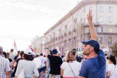Minsk Belarus - Ağustos 2020: Beyaz Rusya 'da barışçıl protestolar. Belarus 2020 'de başkanlık seçimleri. Cumhurbaşkanı adayı Svetlana Tikhanovskaya 'nın destekçileri Minsk' te düzenlenen mitingde. Kalabalıkta zafer işareti gösteren bir adam. Yatay fotoğraf