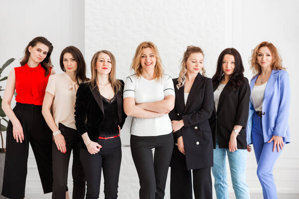 группа женщин, одетых в бизнес-стиль позирующих и смотрящих в камеру. Горизонтальное фото