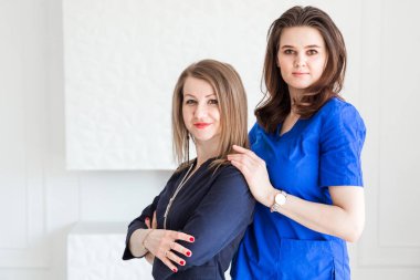 Mavi üniformalar içinde beyaz duvar arkasına poz veren güzel genç bayan doktorlar. Yatay fotoğraf