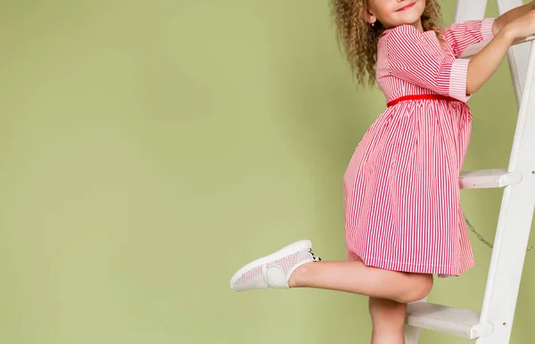 Dziewczyna Czerwonej Sukience Pozuje Schodach Podnosząc Nogę Popisując Się Białymi — Zdjęcie stockowe