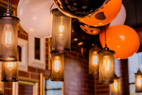 Electric lamps and balloons as Halloween decor in a cafe. Horizontal photo