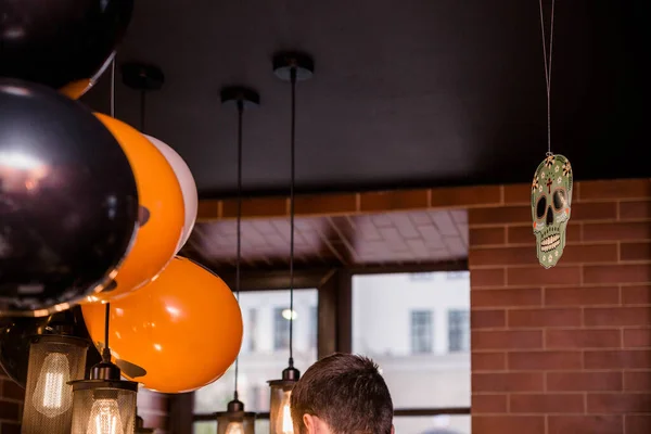 Electric lamps and balloons as Halloween decor in a cafe. Horizontal photo