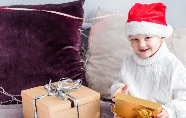 Niño Sombrero Santa Claus Sienta Sofá Con Regalo Las Manos —  Fotos de Stock