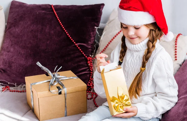 Una Chica Sombrero Santa Claus Sienta Sofá Abre Regalo Año —  Fotos de Stock