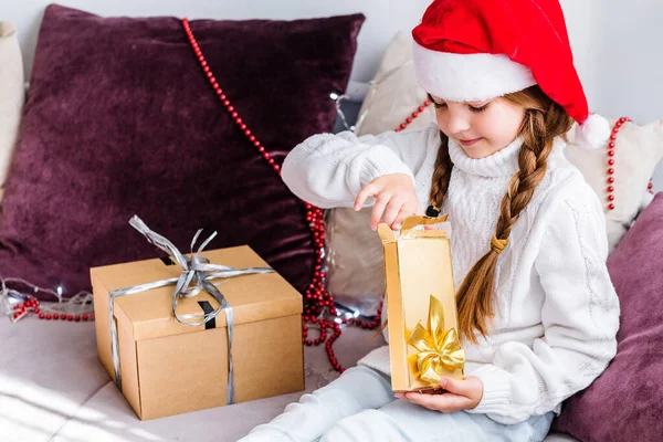 Una Chica Sombrero Santa Claus Sienta Sofá Abre Regalo Año —  Fotos de Stock
