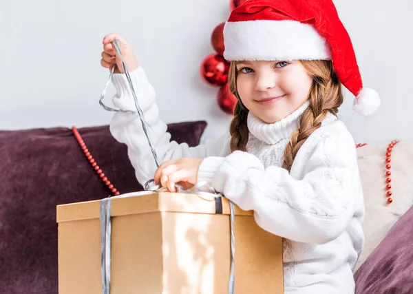 Una Chica Con Sombrero Santa Claus Sienta Sofá Desempaca Una —  Fotos de Stock